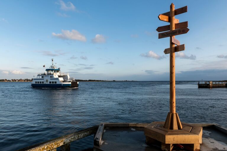 Scenic view of a ferry near Årøsund, Denmark with a wooden direction signpost.