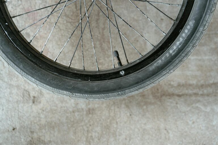 Detailed close-up of a bicycle wheel showing the spokes and valve on a concrete surface.