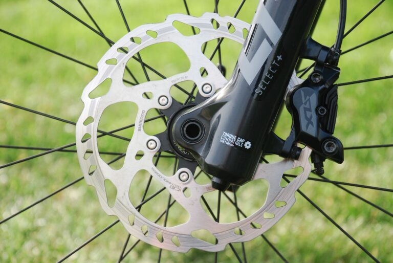 Detailed image of a mountain bike disc brake on a grassy background.