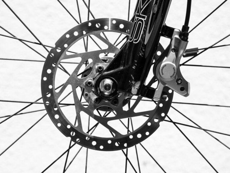 Detailed black and white image of a bicycle wheel highlighting disc brakes and spokes.
