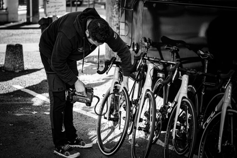 A man in a hoodie examining a row of road bicycles outdoors.