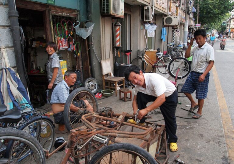 Local bicycle repair in Shanghai's bustling street, capturing everyday life.