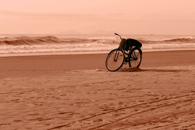 A solitary bicycle rests on a tranquil Guaratuba beach at sunset, capturing a peaceful moment.