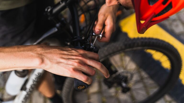 Detailed shot of a person adjusting a bicycle handlebar outdoors in daylight.
