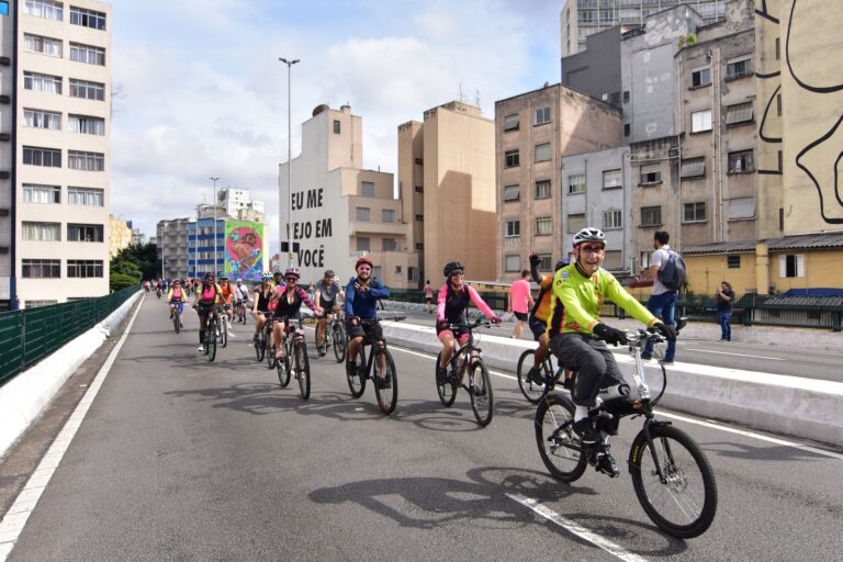 A group of cyclists enjoying a leisurely ride through a bustling urban street with colorful murals.