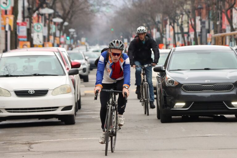 Two cyclists ride through a busy Montréal street, showcasing urban cycling in Canada.