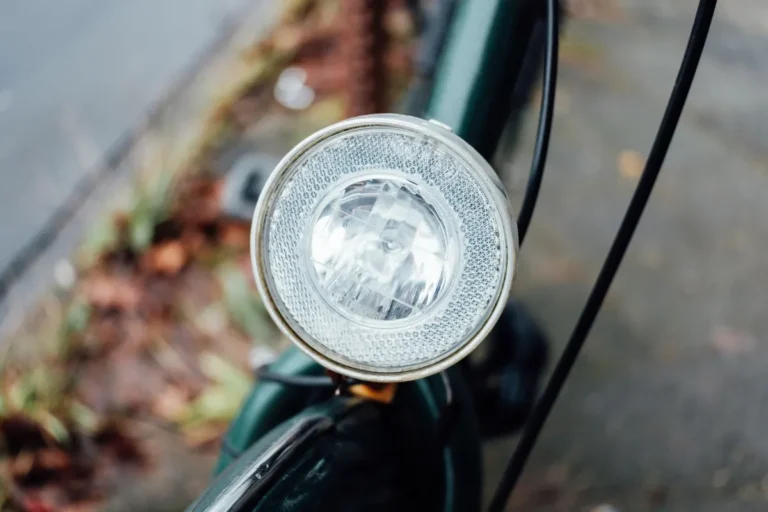 Detailed close-up of a bicycle headlight against an urban outdoor backdrop, showing clear lens design.